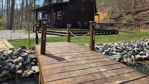 Una baita con un pontile di legno che conduce a un molo, immersa in una zona boschiva.