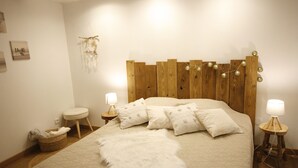 Un dormitorio ordenado con cabecera de madera, un suave plaid blanco y dos lámparas de noche.