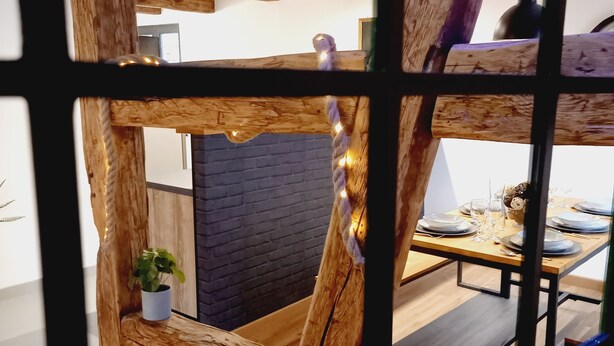 Un interior rústico de madera con vigas a la vista, una pared de ladrillo y un área de comedor con una mesa para dos.
