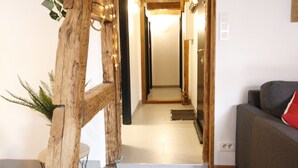 Una escalera de madera que conduce a un pasillo con un sofá gris y un cojín rojo.