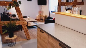 Una cocina moderna con vigas de madera, un televisor y una zona de comedor con sofá y mesa.
