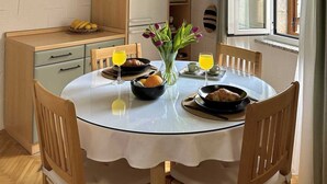 Un coin repas avec une table ronde, des chaises, une horloge et un luminaire suspendu moderne.