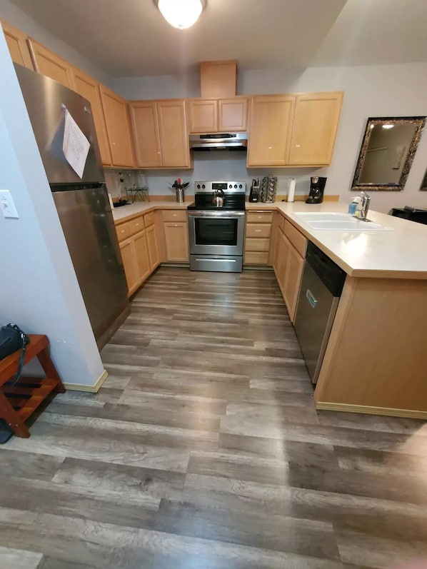 A modern kitchen with wooden cabinets, stainless steel appliances, and a central island.