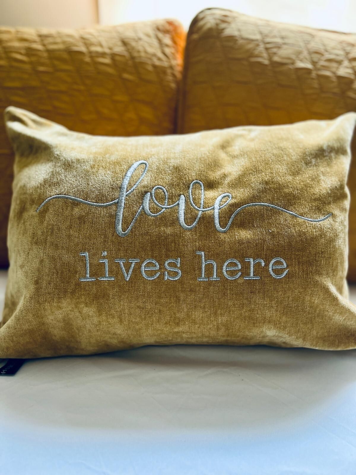 Un coussin orné d’un texte brodé : « L’amour est ici ».