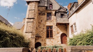 Ein Gebäude aus Stein mit einem Turm, Bogenfenstern und einem Holzzaun.
