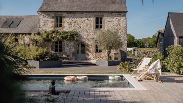 Ein Steinhaus mit Swimmingpool, Sitzgelegenheiten im Freien und einem gepflegten Garten.