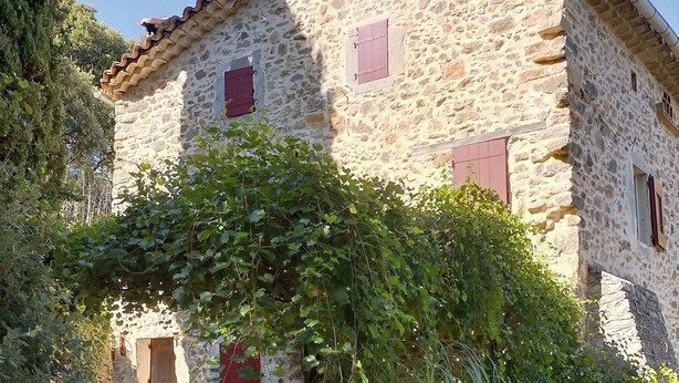 A stone building with a tiled roof, a wooden door, and a small window.