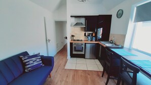 Un espacio habitable compacto con kitchenette, sofá y comedor.