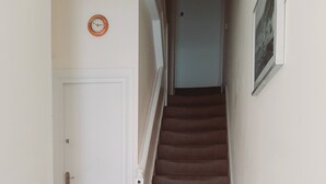 Una escalera con un rellano alfombrado y una puerta blanca con felpudo.
