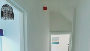 Un pasillo estrecho con piso de madera que conduce a un dormitorio con cama y mesita de noche.