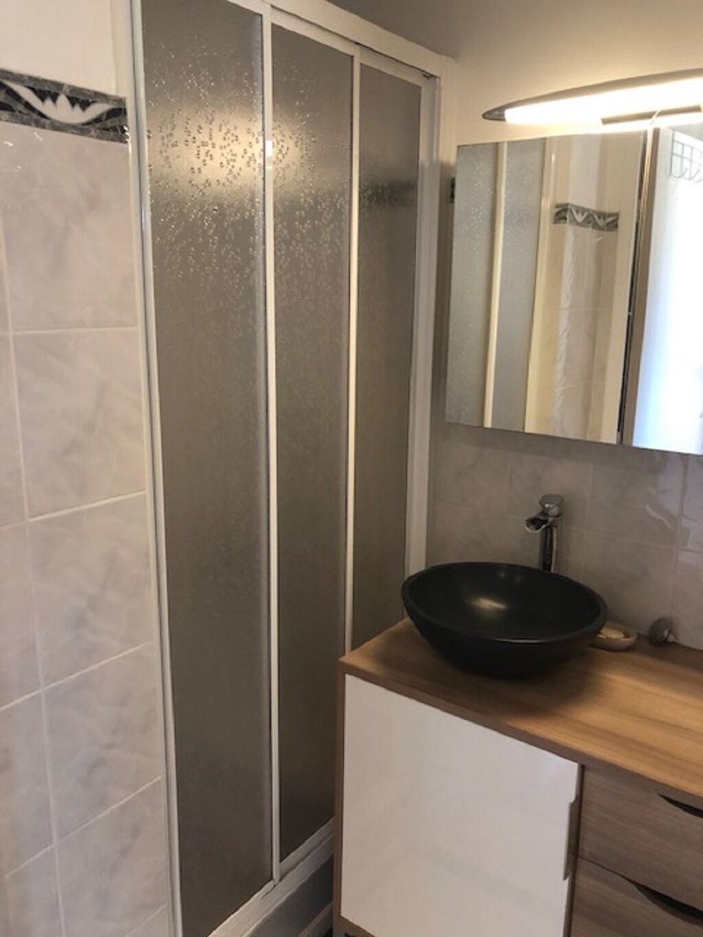 Een badkamer met een douchecabine, een wastafel en een spiegel.