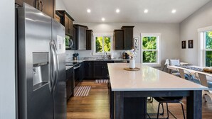 Una cocina moderna con gabinetes oscuros, electrodomésticos de acero inoxidable y una isla grande.