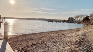 A waterfront scene with a wooden dock extending into calm water, a clear sky, and a distant shoreline with buildings. - Private home, short walk to Harbour Island beach! Central A/C, family friendly! (Narragansett)