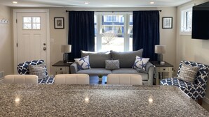 A modern living room with a large grey sofa, two armchairs, a coffee table, and a TV mounted on the wall. - Private home, short walk to Harbour Island beach! Central A/C, family friendly! (Narragansett)