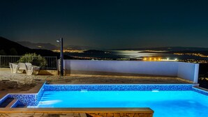 Ein Schwimmbad mit Blick auf eine nächtliche Stadtlandschaft.