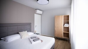 Une chambre moderne avec un grand lit, une armoire en bois et un luminaire suspendu au plafond.