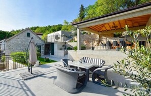 A patio area with outdoor furniture, a stone wall, and a covered seating area. - Cozy home in Donji Prolozac (Donji Prolozac)
