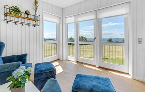 A spacious room with large windows, a wooden floor, and blue upholstered furniture. - Gorgeous home in Faaborg with sauna (Faaborg)