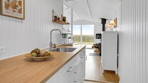 Une cuisine moderne avec des meubles blancs, un plan de travail en bois et une vue sur l’extérieur.