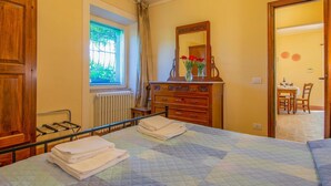 Une chambre à coucher avec un lit, une commode, une fenêtre, un radiateur et un miroir.