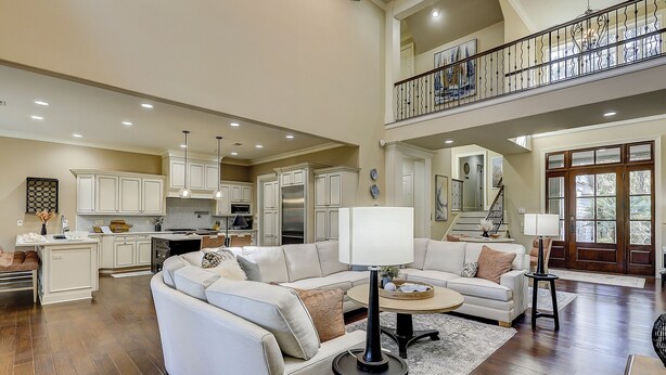 A spacious living room with a high ceiling, a kitchen with white cabinets, and a balcony with a railing. - 13 Wagon Rd. Vacation paradise! Close to the beach! Water view! (Hilton Head Island)