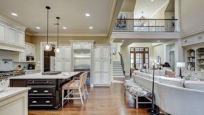 A spacious kitchen with a large island, wooden flooring, and a view of a balcony. - 13 Wagon Rd. Vacation paradise! Close to the beach! Water view! (Hilton Head Island)