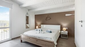 A bedroom with a large bed, two bedside tables, a mirror, and a view of the outdoors. - Gorgeous home in Rosolini (Rosolini)