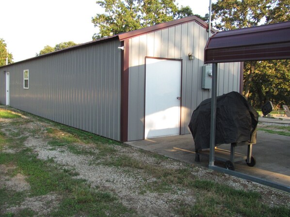 A metal building with a covered entrance and a large grill outside. - Deer Run Retreat Great fishing cabin! (Greenfield)
