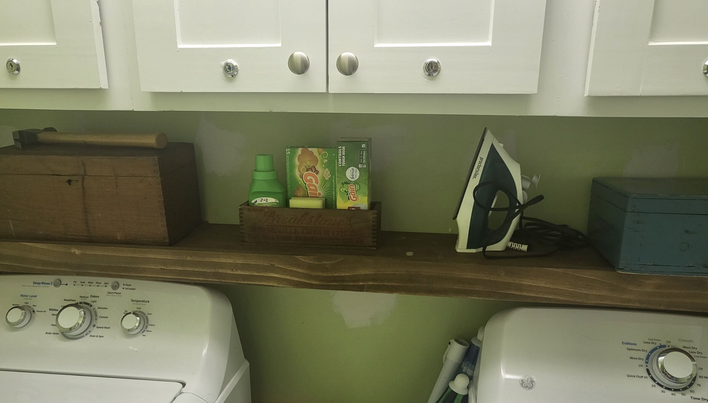 A laundry area with a washing machine, a dryer, and a shelf with cleaning supplies.