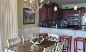 Una cocina con armarios de madera, horno de acero inoxidable y mesa de vidrio con sillas.