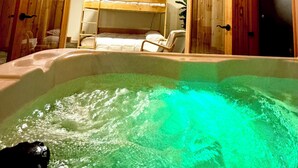 A wooden cabin interior with a hot tub, bunk beds, and a ceiling light fixture. - 30 acres, steam sauna, hot tub, 7 beds, sleeps 10. We LOVE dogs! (Onekama)
