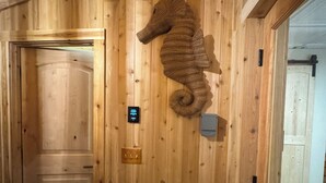 Interior de madera con una decoración de caballito de mar, una puerta y un interruptor de luz.