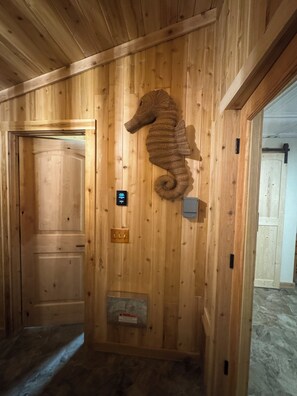 A wooden interior with a seahorse decoration, a door, and a light switch.