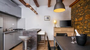 A modern kitchen with a central island, bar stools, a dining table with chairs, a TV, and a stone wall. - Amazing home in Barban with sauna (Barban)