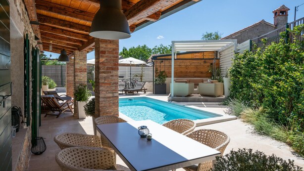 A covered outdoor area with a pool, wicker furniture, and a table with a candle. - Amazing home in Barban with sauna (Barban)