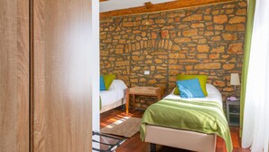 A room with two beds, a stone wall, wooden beams, and a small wooden stool. - Amazing home in Barban with sauna (Barban)