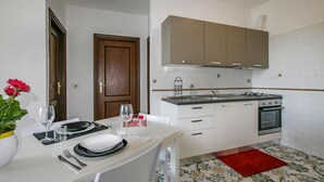Cocina compacta con armarios blancos, estufa y lavamanos.