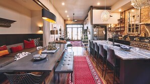 A modern kitchen with a central island, bar seating, and a dining area with a red carpet. - Luxurious industrial-chic loft in historic downtown Sheridan. This stunning 2-bedroom, 2-bath apartment sleeps up to 9, featuring 2 king suites, 2 1/2 bathrooms sleeping alcove, modern kitchen, fireplace, & Main Street balcony views. (Sheridan)