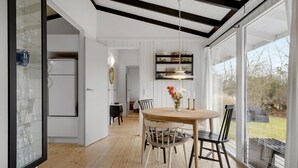 Een moderne keuken met witte kastjes, een inbouwoven en een eethoek met een ronde tafel en stoelen.