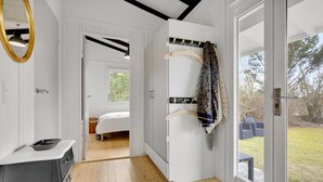 Een moderne slaapkamer met een bed, een houten vloer, een witte kledingkast en een kapstok met een geruit kledingstuk.