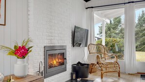 Een gezellige kamer met een open haard, een televisie, rieten stoelen en uitzicht op de omgeving.