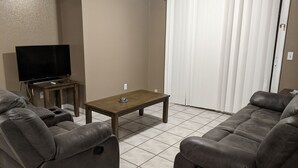 A living room with a flat-screen TV, a wooden coffee table, and two gray sofas. - Snowbirds escape / vacation gateway (Englewood)