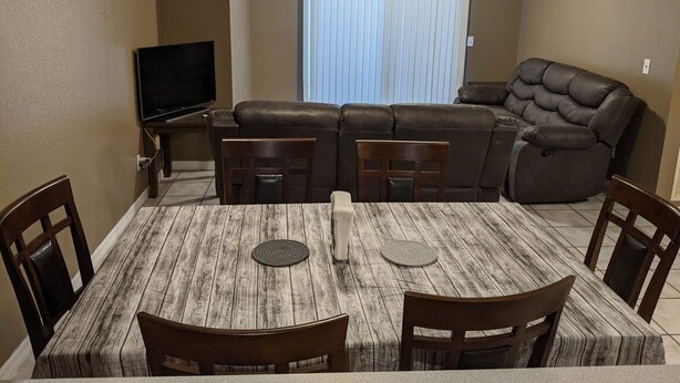 A living room with a sectional sofa, a flat-screen TV, and a dining table with chairs. - Snowbirds escape / vacation gateway (Englewood)