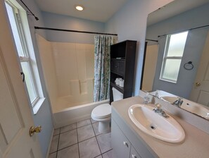 Ein Badezimmer mit einer Badewanne, Toilette und einem Waschtisch mit Waschbecken und Spiegel.