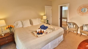 A hotel room with a large bed, bedside lamps, a small table with a vase of flowers, and a chair.
