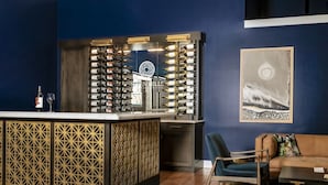 A bar area with a wine rack, a sofa, and a painting on the wall.