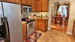 A kitchen with wooden cabinets, stainless steel appliances, and a dining area with a wooden table and chairs.