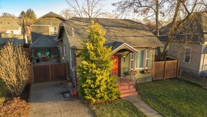 A residential house with a front yard, a wooden deck, and a small tree.