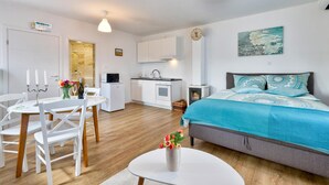 Une chambre moderne et bien éclairée, comprenant un lit, un coin repas et une kitchenette.