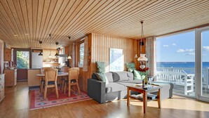 Un intérieur en bois comprenant un coin repas, un canapé et une vue sur la mer.